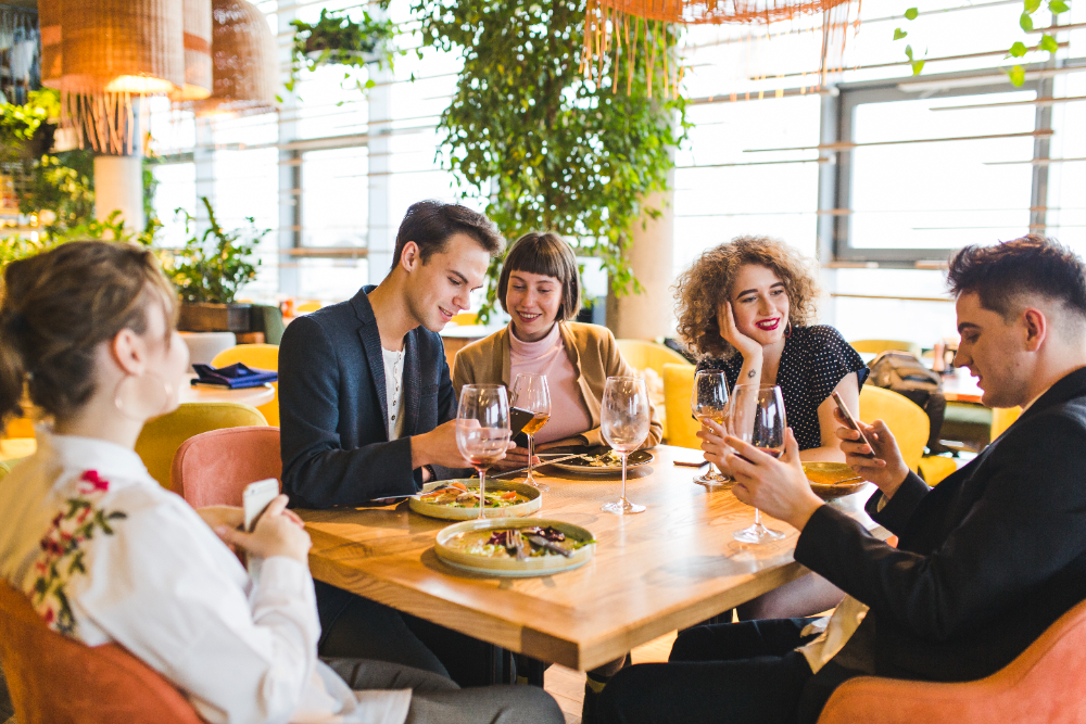 gasten rondom een tafel met eten en wijn in een restaurant. afbeelding voor gasttevredenheidsonderzoek